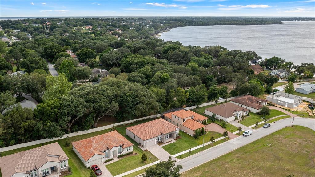 An aerial view shows several suburban houses with tile roofs near a large lake — 12919 BRUNELLO CIRCLE, CLERMONT, FL