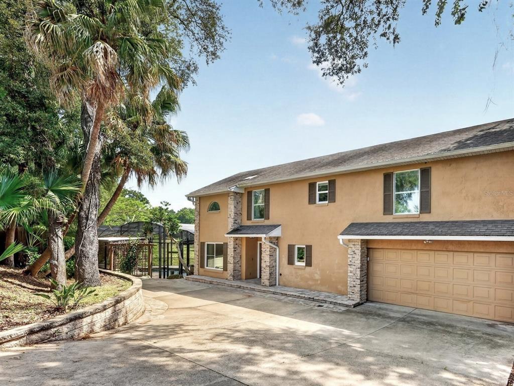 A two-story tan stucco house with a stone-accented entryway and an attached two-car garage — 1625 ABRAMS ROAD, EUSTIS, FL