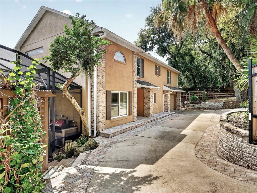 A two-story stucco house with stone accents, a paved driveway, and a screened-in patio area — 1625 ABRAMS ROAD, EUSTIS, FL