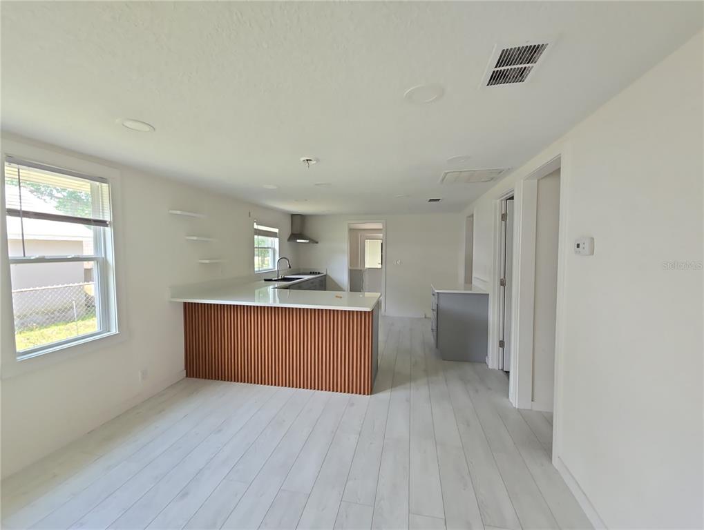 A kitchen with a slatted wood island, white countertops, and light wood-look flooring — 1626 GAR STREET, ST CLOUD, FL