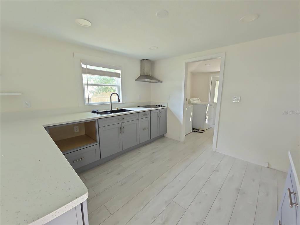 A kitchen features light gray cabinets, white countertops, a stainless steel range hood, and light flooring — 1626 GAR STREET, ST CLOUD, FL