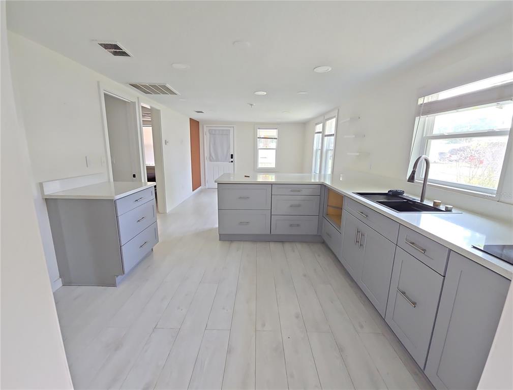 A kitchen with light gray cabinets, white countertops, and light wood-look flooring — 1626 GAR STREET, ST CLOUD, FL