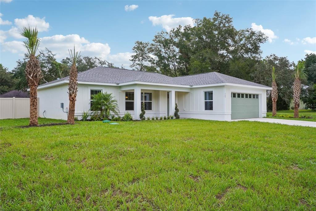 A white single-story house with a green garage door and palm trees on a lawn — 509 W WASON STREET, CITRUS SPRINGS, FL