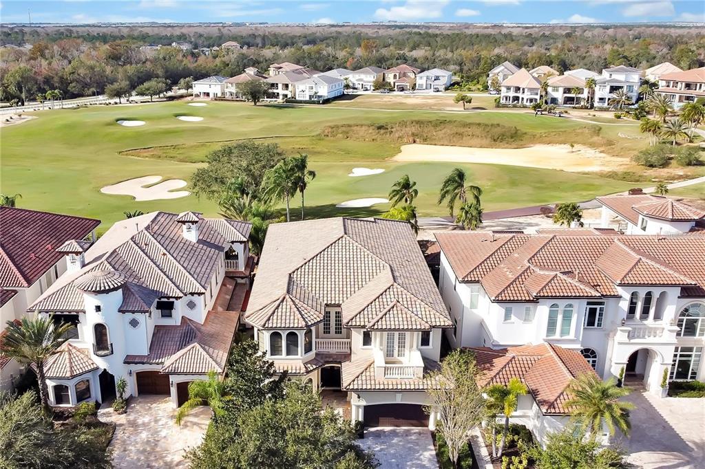 An aerial view shows three large houses with tiled roofs overlooking a golf course — 420 MUIRFIELD LOOP, REUNION, FL