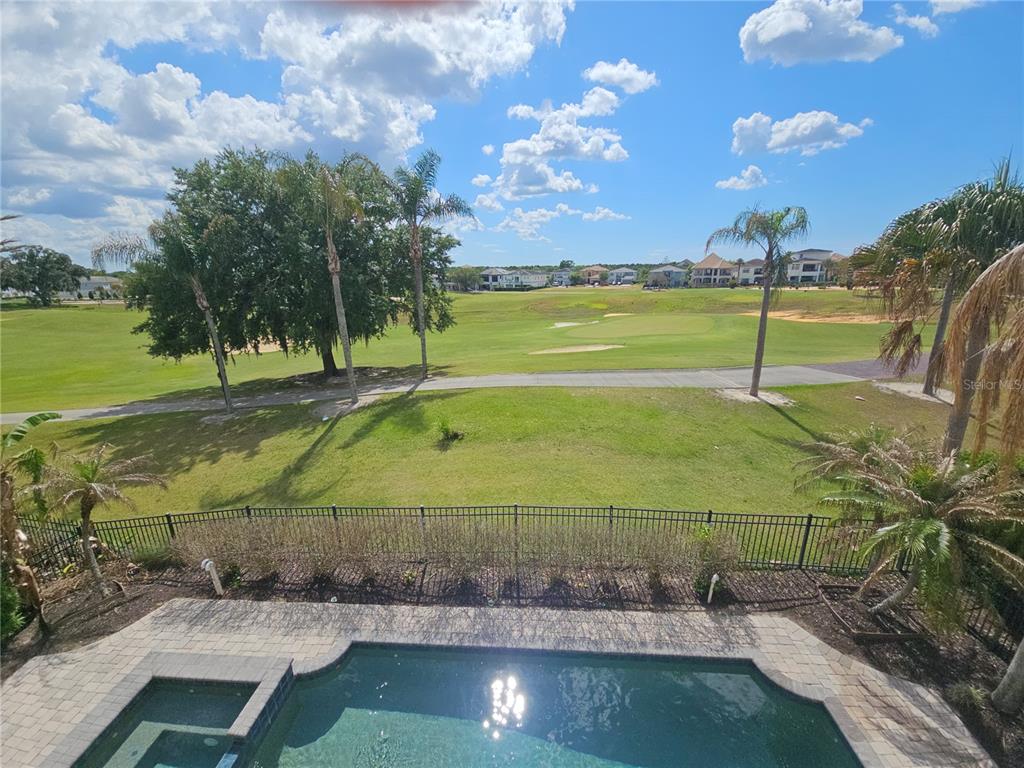 An elevated view of a swimming pool overlooking a golf course and residential homes — 420 MUIRFIELD LOOP, REUNION, FL