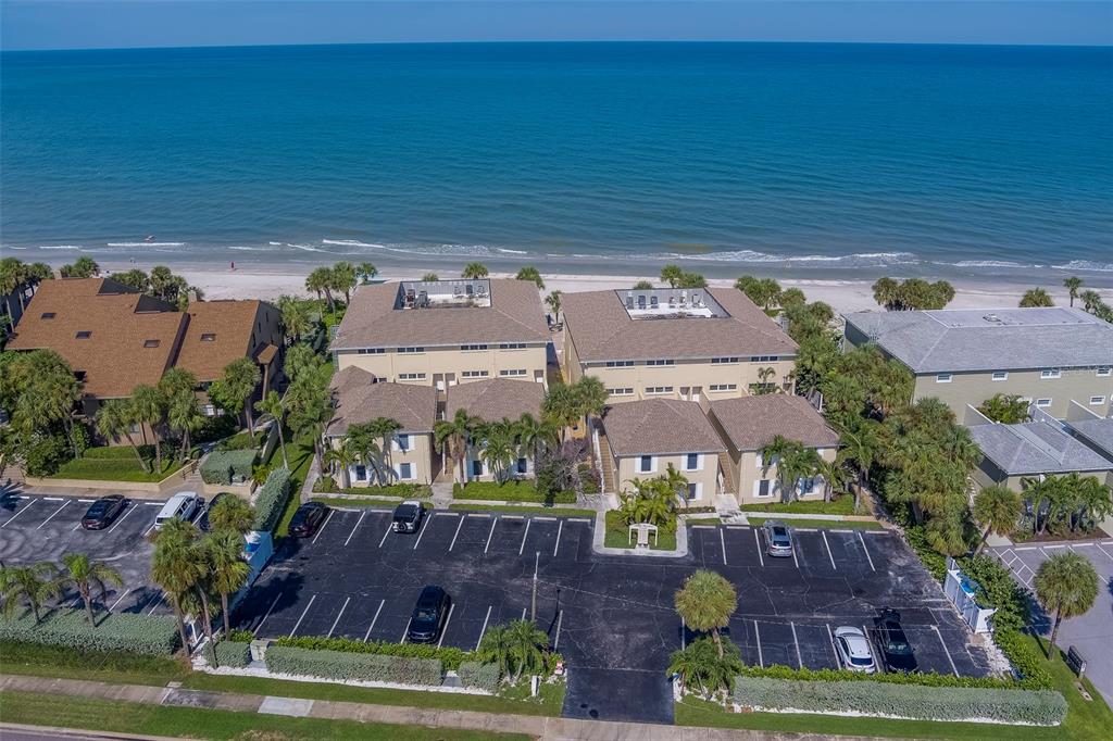 An aerial view shows two multi-story beachfront buildings with a parking lot in the foreground — 2250 GULF BOULEVARD UNIT B2, BELLEAIR BEACH, FL