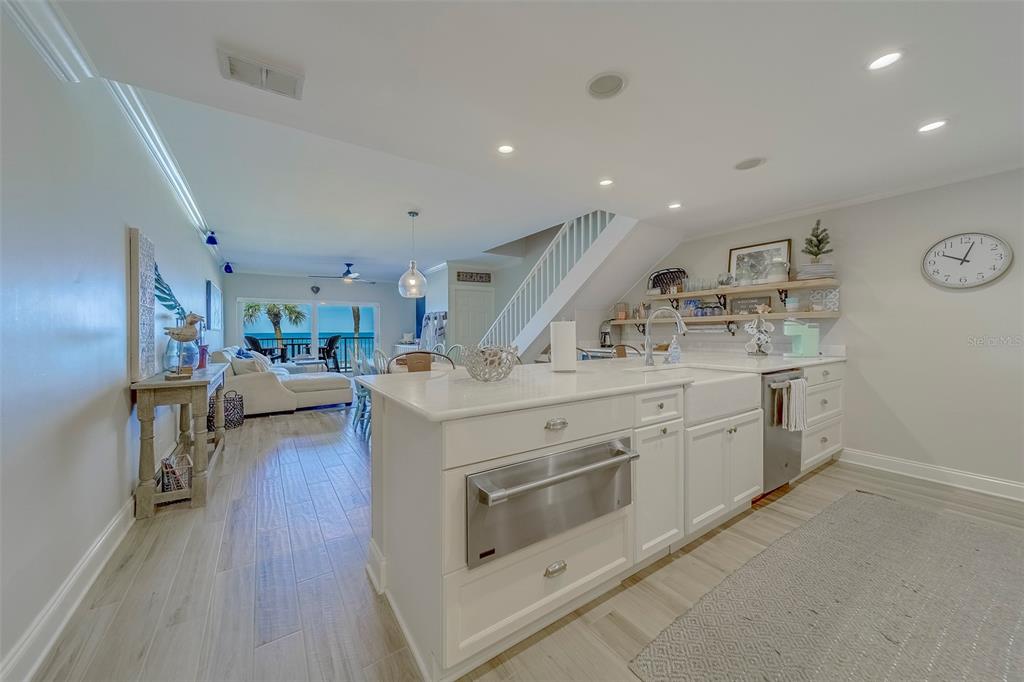 A bright kitchen features white cabinetry, a large island, and an open view of the ocean — 2250 GULF BOULEVARD UNIT B2, BELLEAIR BEACH, FL