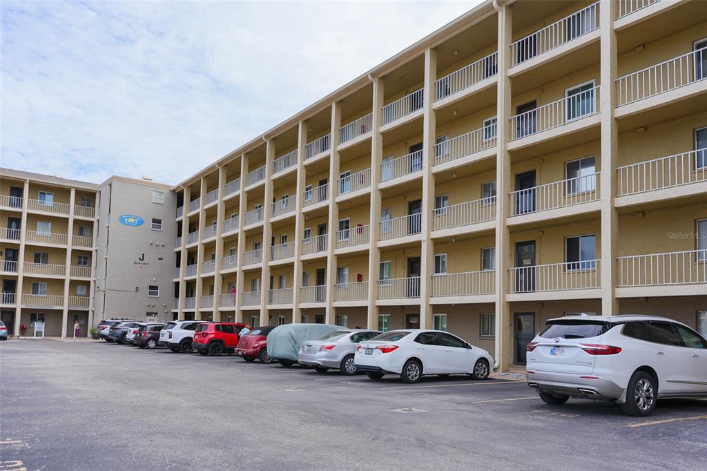 A multi-story apartment building with exterior walkways and a parking lot in the foreground — 3607 LAKE BAYSHORE DRIVE UNIT J-312, BRADENTON, FL