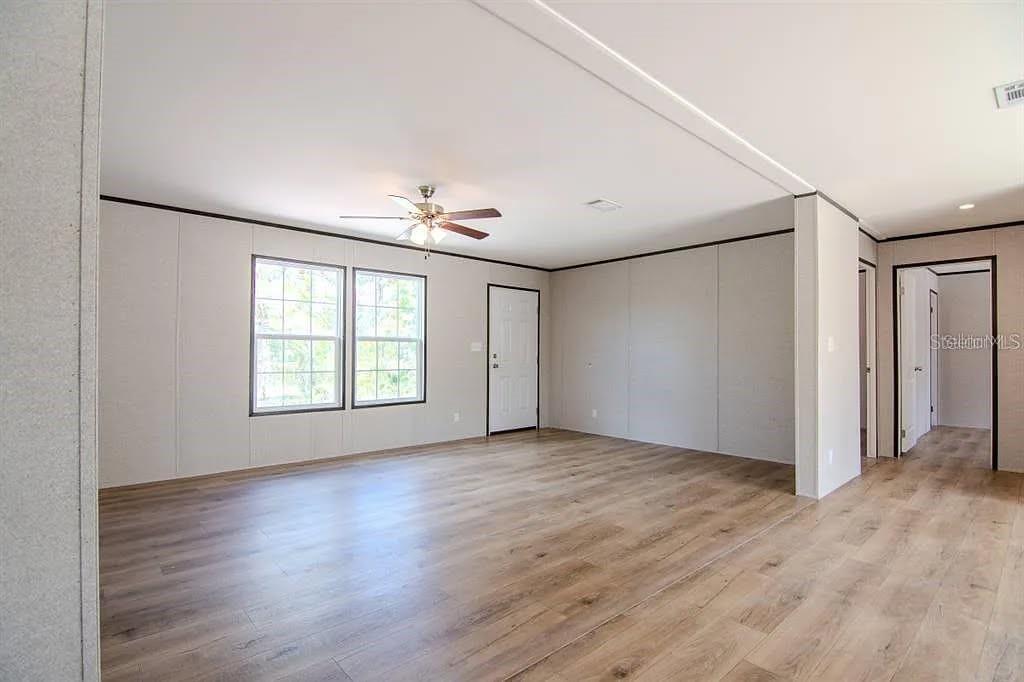 An open-concept living area features light wood-look flooring, a kitchen with white cabinets, and a ceiling fan — 19732 NW 280TH STREET, OKEECHOBEE, FL