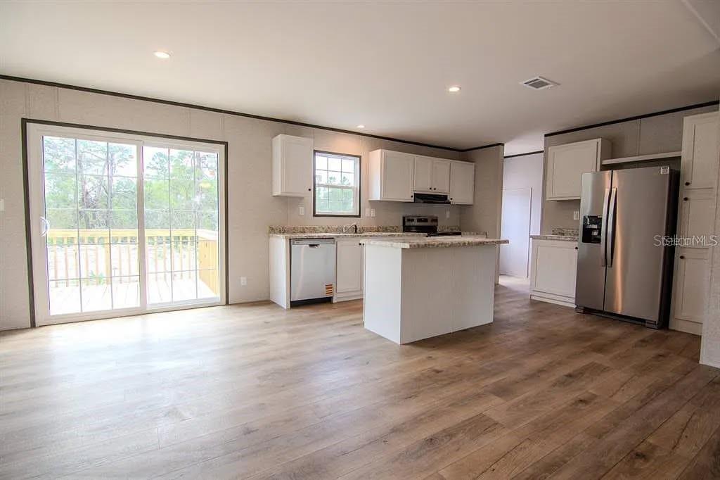 An empty bedroom features light-colored paneled walls, wood-look flooring, and a ceiling fan — 19732 NW 280TH STREET, OKEECHOBEE, FL