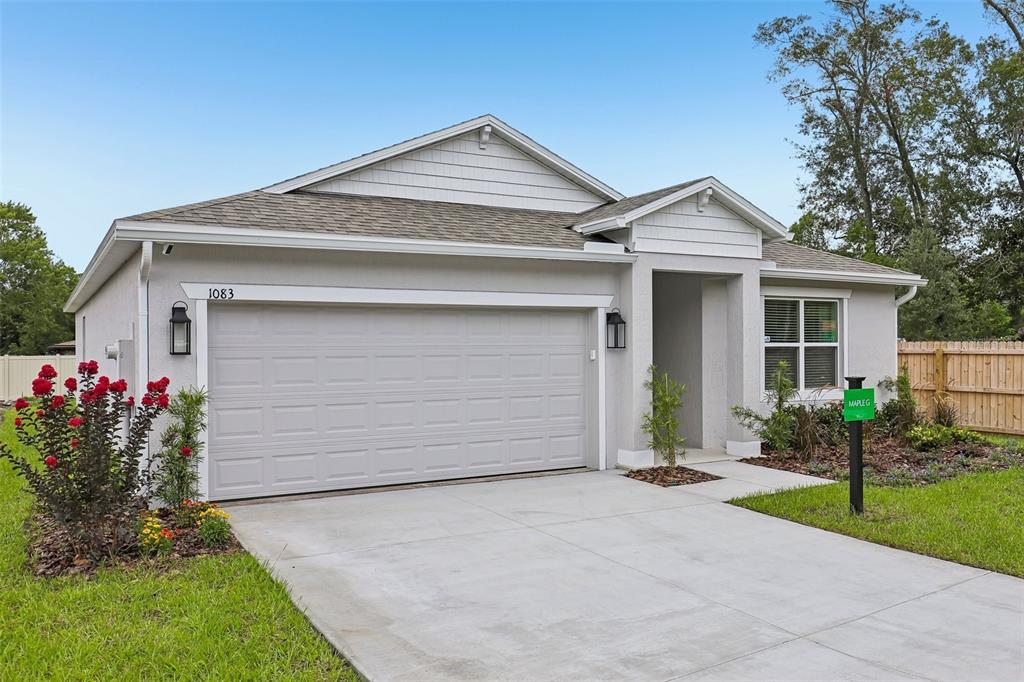A single-story house with a two-car garage, light-colored stucco siding, and a concrete driveway — 1407 NEEDLE PALM DRIVE, EDGEWATER, FL