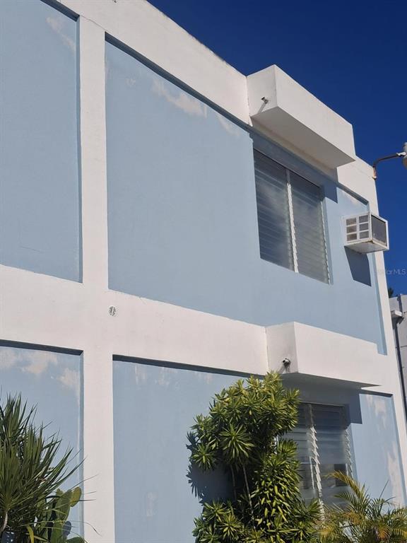 A two-story light blue building exterior features white trim, louvered windows, and a window air conditioner — FJQ2+FGJ MANUEL OTERO UNIT 3, VEGA BAJA, PR