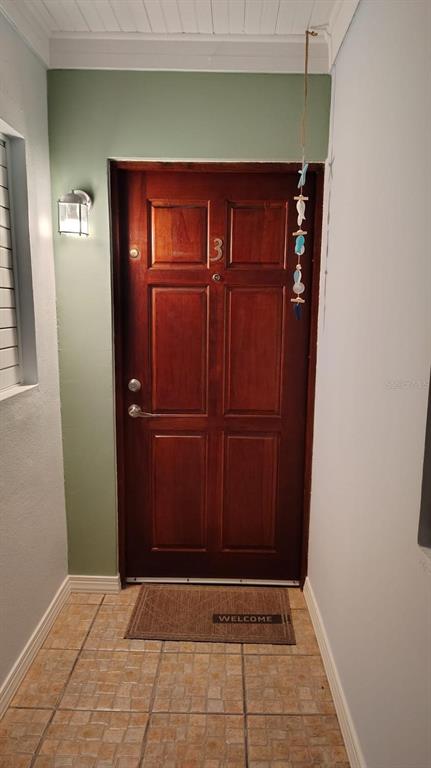 A wooden front door with a number three is centered in a small tiled entryway — FJQ2+FGJ MANUEL OTERO UNIT 3, VEGA BAJA, PR