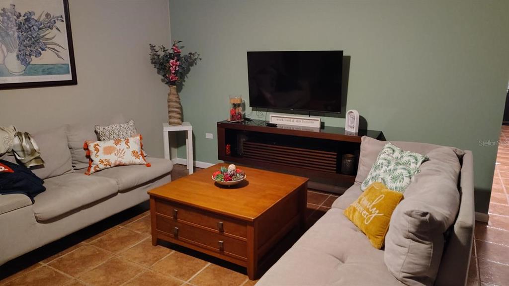 A living room features two sofas, a wooden coffee table, and a television on a console — FJQ2+FGJ MANUEL OTERO UNIT 3, VEGA BAJA, PR