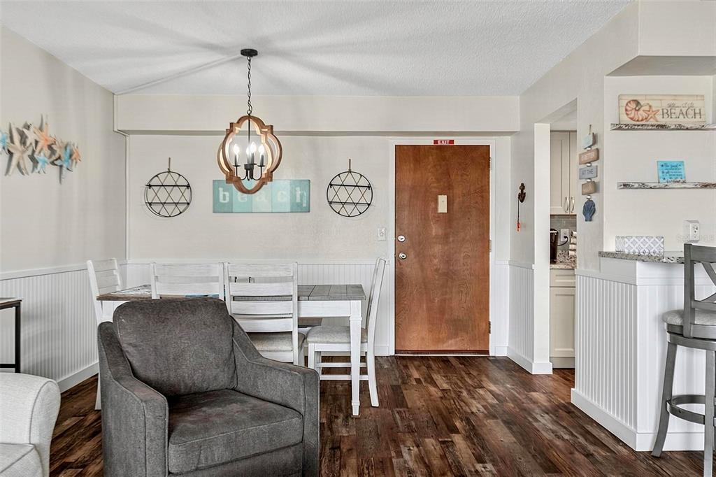 A dining area with a wooden door, a chandelier, and a gray armchair in the foreground — 3600 S OCEANSHORE BOULEVARD, FLAGLER BEACH, FL