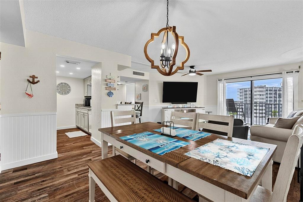 A dining area with a wooden table and bench sits before a living room and balcony — 3600 S OCEANSHORE BOULEVARD, FLAGLER BEACH, FL