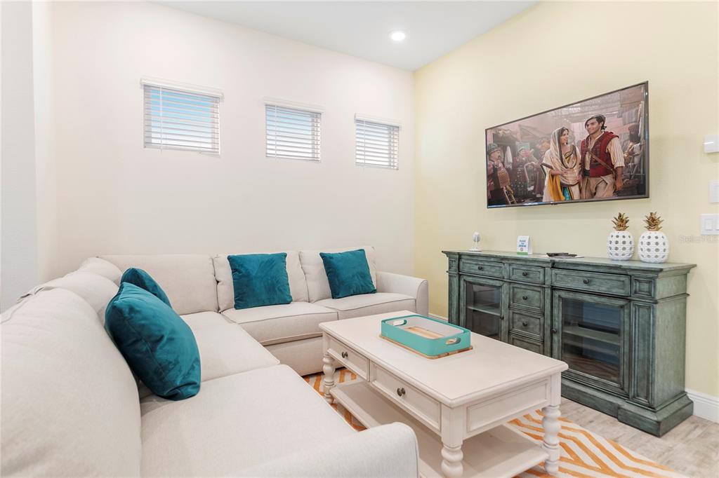 A living room features a beige sectional sofa, a coffee table, and a teal media console — 8041 LOST SHAKER LANE, KISSIMMEE, FL