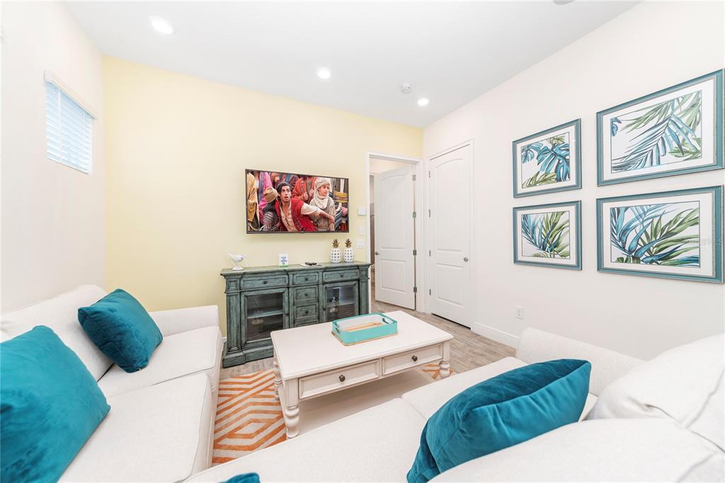 A living room features a white sofa with teal pillows, a TV, and wall art — 8041 LOST SHAKER LANE, KISSIMMEE, FL