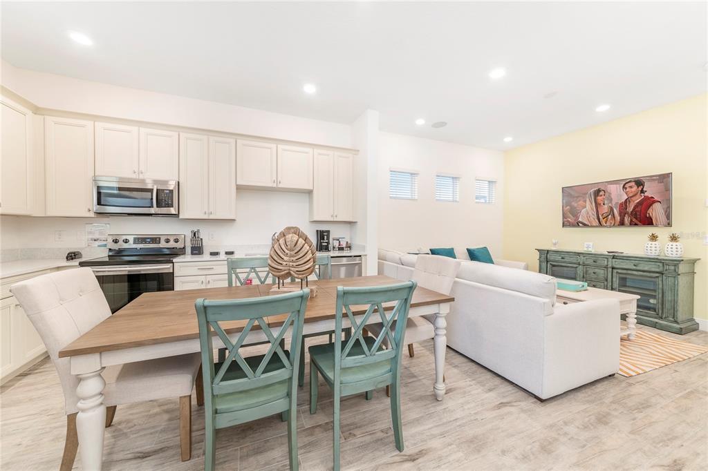 A kitchen and dining area open to a living room with light-colored furniture — 8041 LOST SHAKER LANE, KISSIMMEE, FL