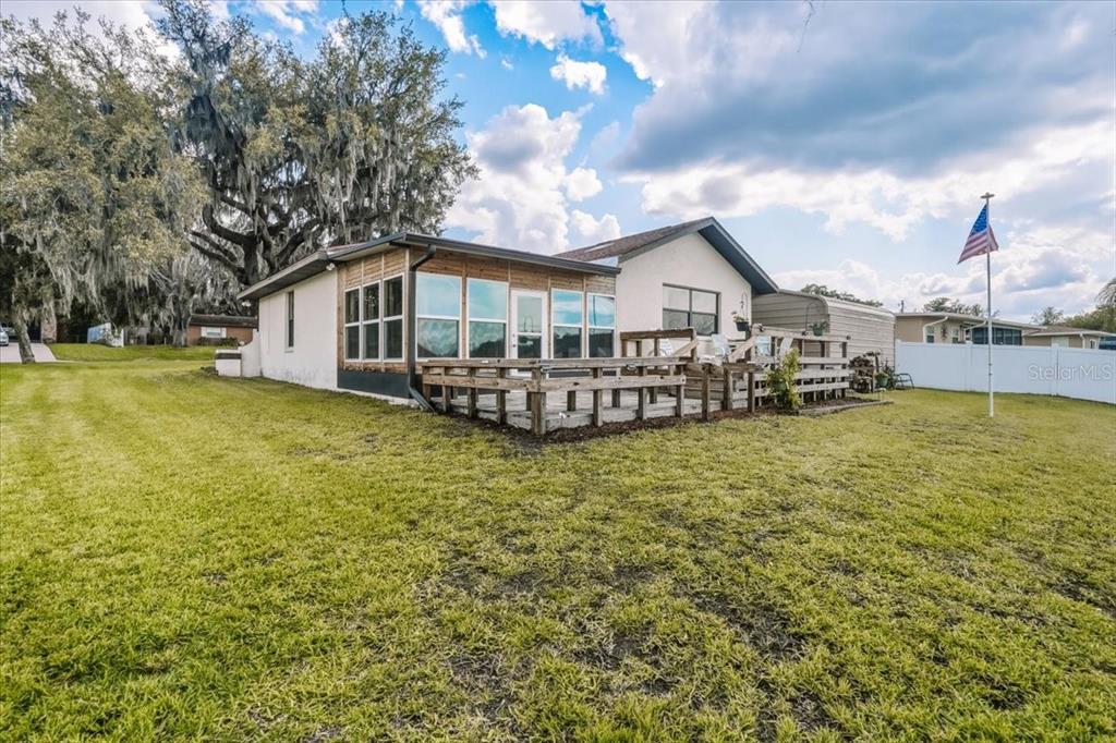 A house exterior features a wooden deck and a sunroom with large windows — 9103 E AQUA VISTA DRIVE, INVERNESS, FL