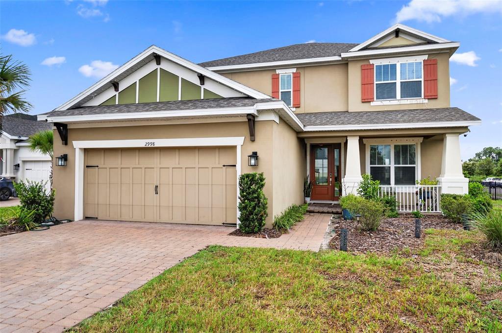 A two-story suburban house with a tan stucco exterior, a two-car garage, and a porch — 2998 LILLA TRAIL, ODESSA, FL
