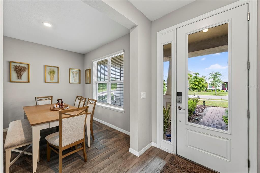 A dining area with wood-look tile floors sits next to a white front door — 2998 LILLA TRAIL, ODESSA, FL