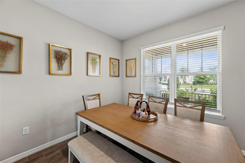 A dining room features a wooden table, chairs, a bench, and framed wall art — 2998 LILLA TRAIL, ODESSA, FL