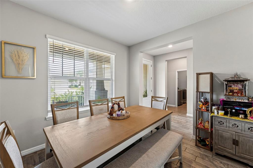 A dining room features a wooden table, a bench, chairs, and a decorative cabinet — 2998 LILLA TRAIL, ODESSA, FL