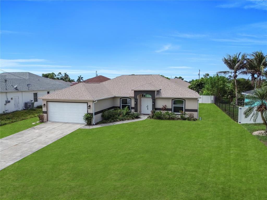 A tan single-story house with a two-car garage and a large front lawn — 2007 NW 21ST ST, CAPE CORAL, FL