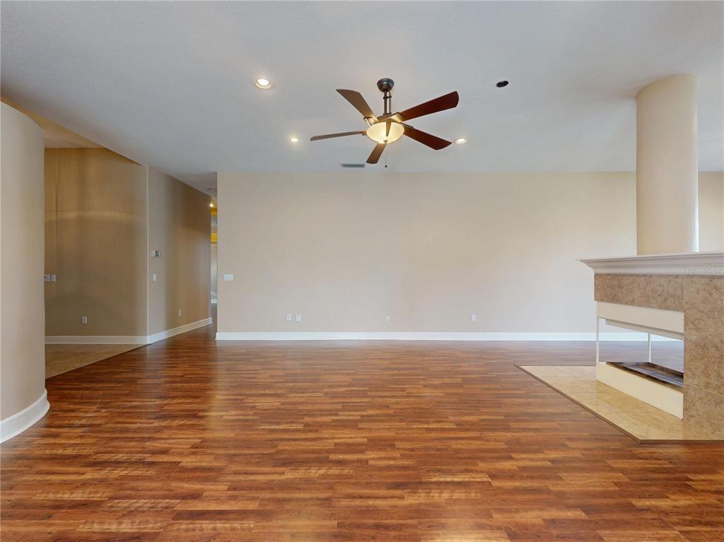 A spacious room features wood-look flooring, a ceiling fan, and a fireplace with a column — 71 CARRIAGE CREEK WAY, ORMOND BEACH, FL