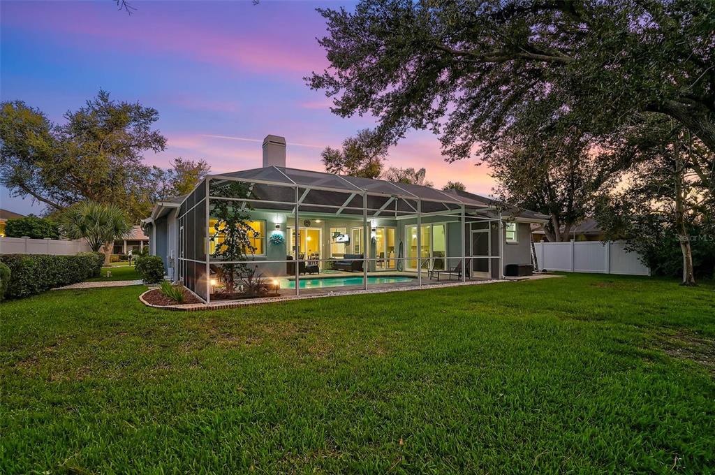The exterior of a house features a screened-in pool and patio area in a backyard — 599 PINE RANCH EAST ROAD, OSPREY, FL