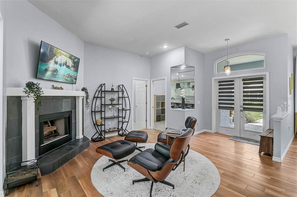 A living room with a fireplace, two lounge chairs, and double glass doors to the outside — 599 PINE RANCH EAST ROAD, OSPREY, FL