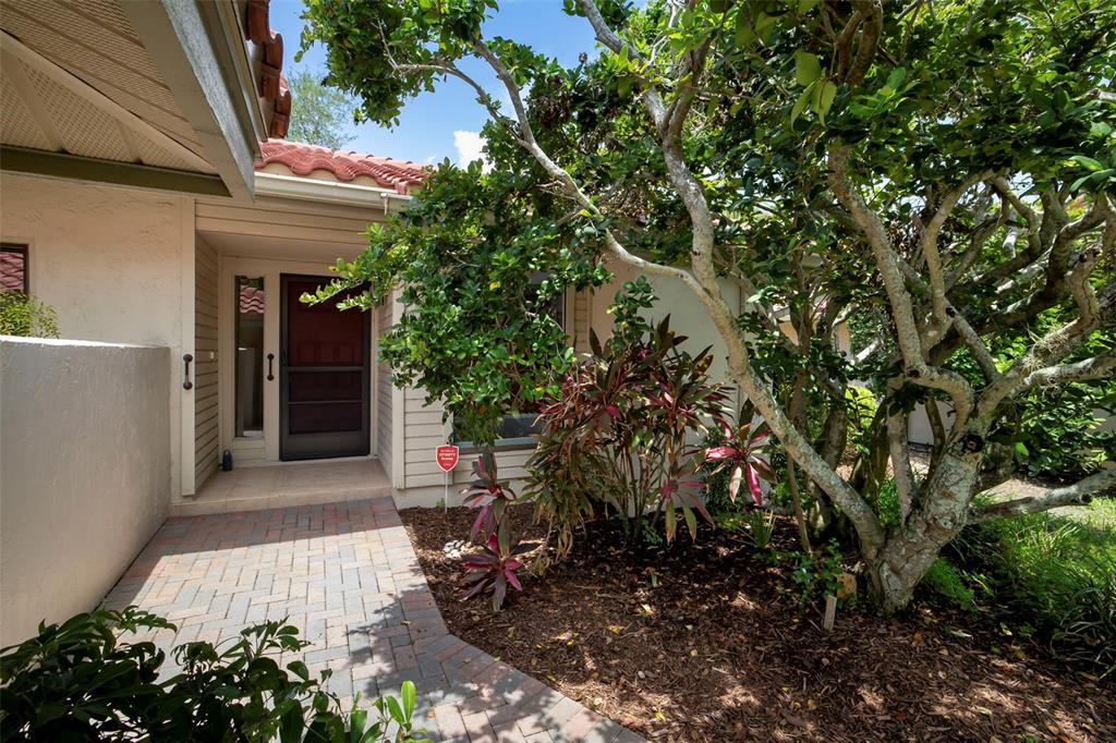 A paved walkway leads to the garage entrance of a house with a tiled roof — 4820 KESTRAL PARK CIRCLE UNIT 18, SARASOTA, FL