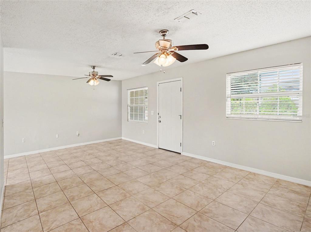 An open-concept living area features light-colored tile flooring, two ceiling fans, and a kitchen — 3255 KELVINGTON DRIVE, ORLANDO, FL