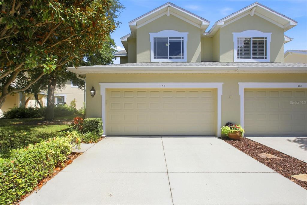 The rear exterior of a two-story house features a screened-in porch and a paved patio — 477 HARBOR RIDGE DRIVE, PALM HARBOR, FL