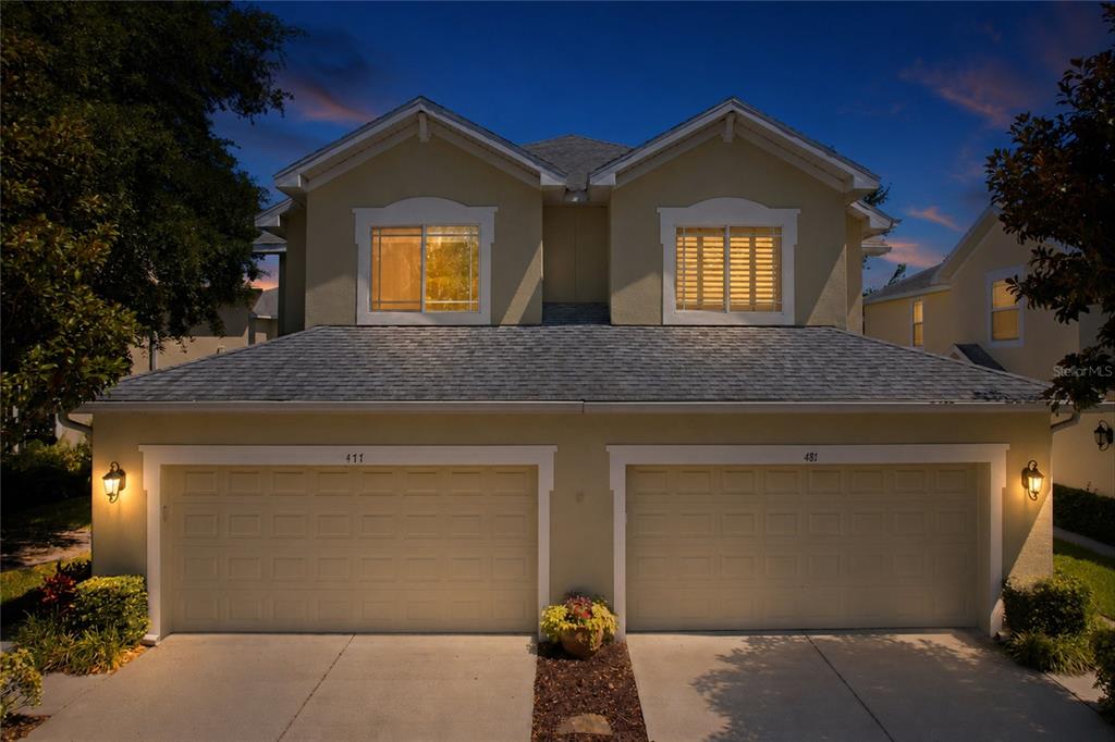 A two-story duplex features two beige garage doors and a central stone walkway — 477 HARBOR RIDGE DRIVE, PALM HARBOR, FL
