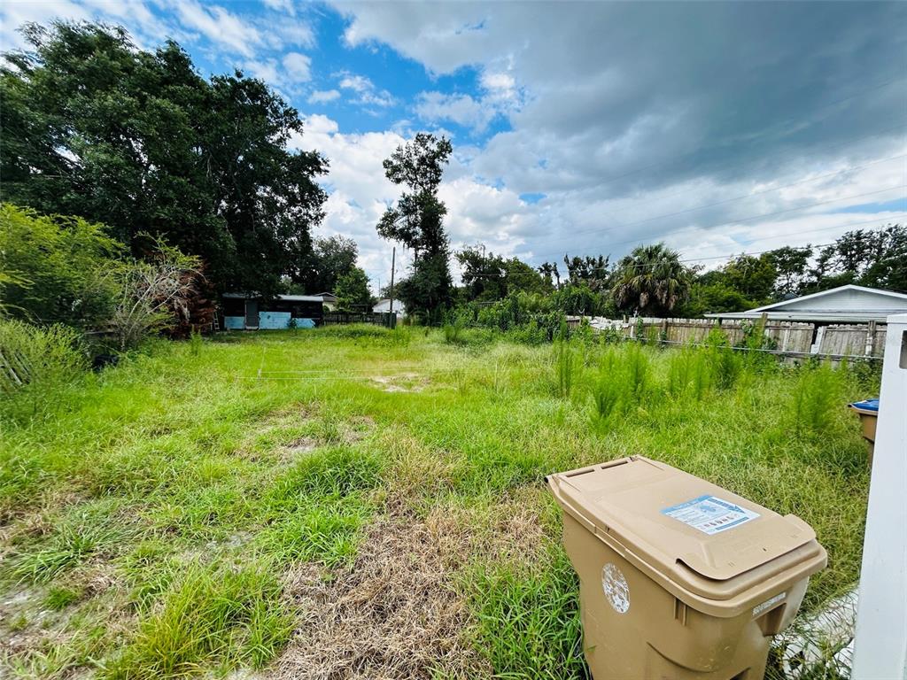 A grassy, overgrown vacant lot with a trash bin in the foreground — 1493 TALLAHASSEE BOULEVARD, INTERCESSION CITY, FL