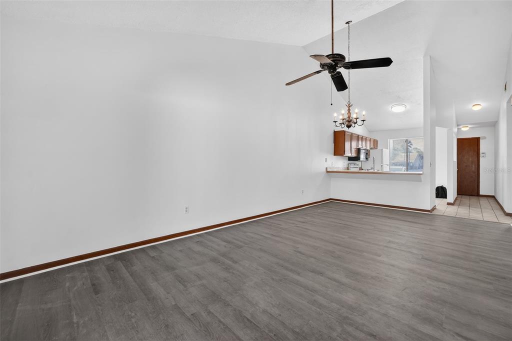 A spacious living area with gray wood-look flooring, white walls, and a vaulted ceiling — 3559 FOREST BRANCH DRIVE Apt E, PORT ORANGE, FL
