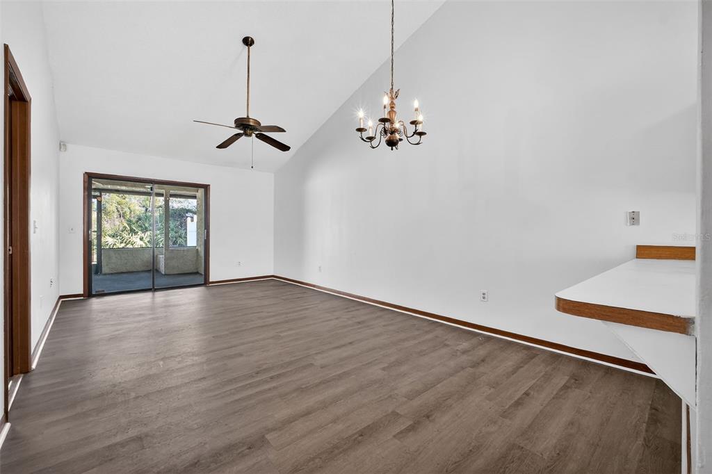 An empty room with vaulted ceilings, wood-look flooring, a ceiling fan, and a chandelier — 3559 FOREST BRANCH DRIVE Apt E, PORT ORANGE, FL