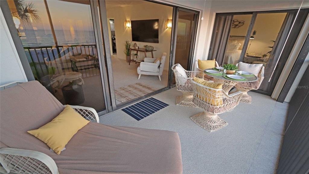 A balcony with a lounge chair and dining set overlooks the ocean through glass doors — 900 GULF BOULEVARD UNIT 302, INDIAN ROCKS BEACH, FL