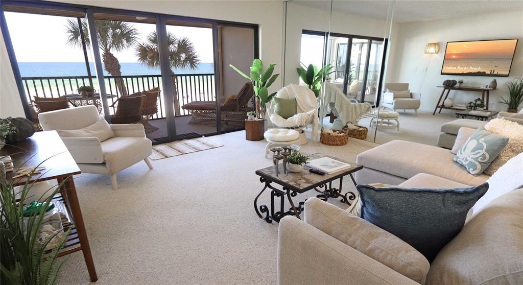 A living room with beige carpet, a sectional sofa, and a balcony overlooking the ocean — 900 GULF BOULEVARD UNIT 302, INDIAN ROCKS BEACH, FL