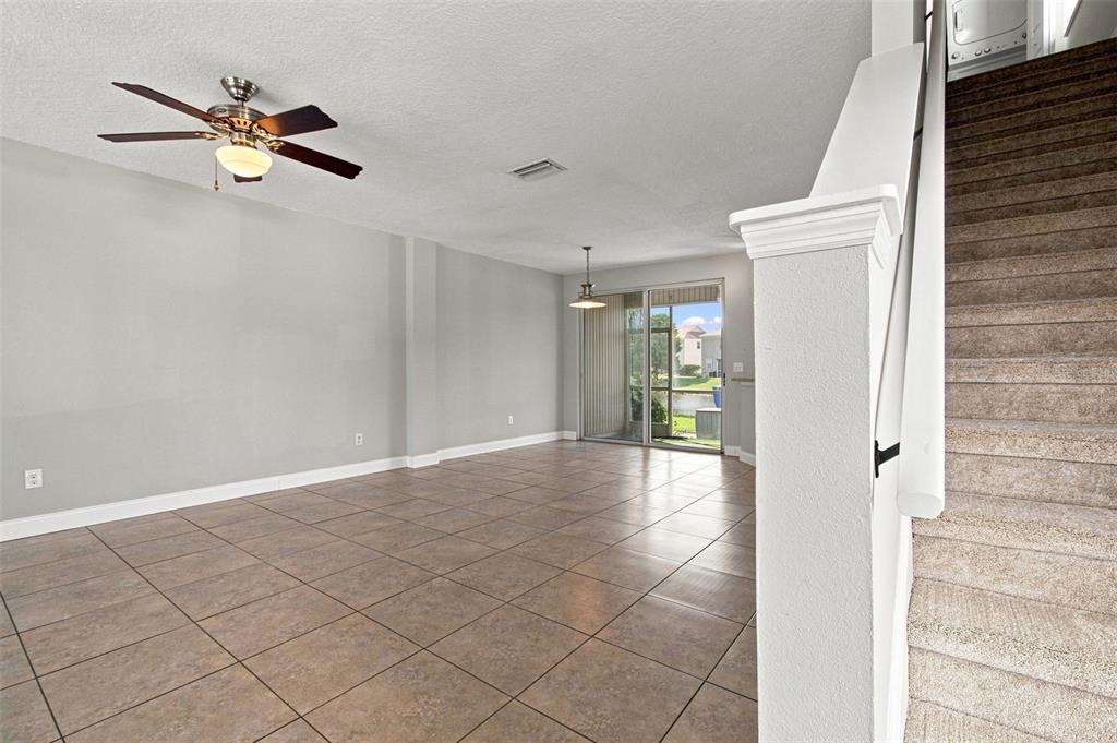 An open living area features tile flooring, a ceiling fan, and carpeted stairs — 12225 COUNTRY WHITE CIRCLE, TAMPA, FL