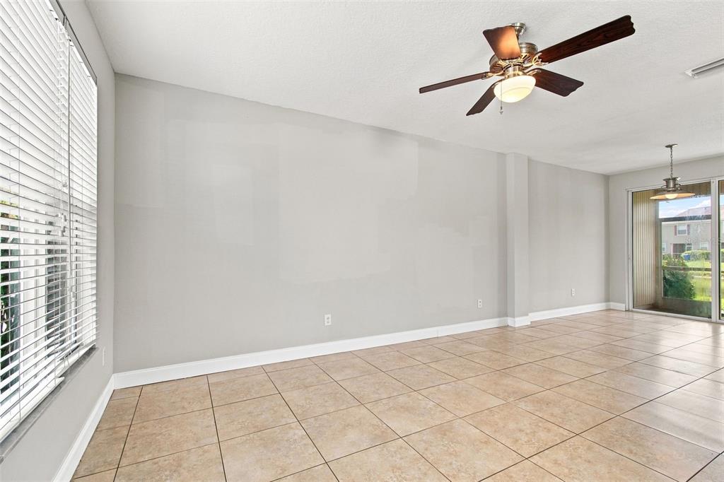 An empty room with light-colored walls, tile flooring, a ceiling fan, and sliding glass doors — 12225 COUNTRY WHITE CIRCLE, TAMPA, FL