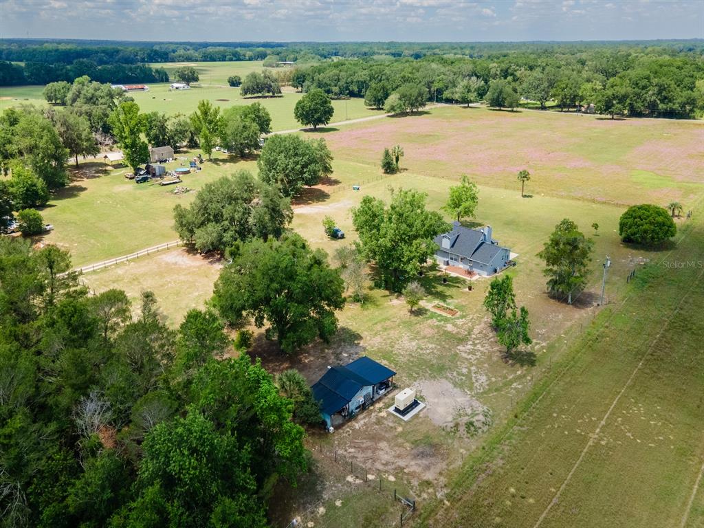 An aerial view shows two houses situated on a large, grassy rural property with trees — 4381 NE 105TH PLACE, ANTHONY, FL