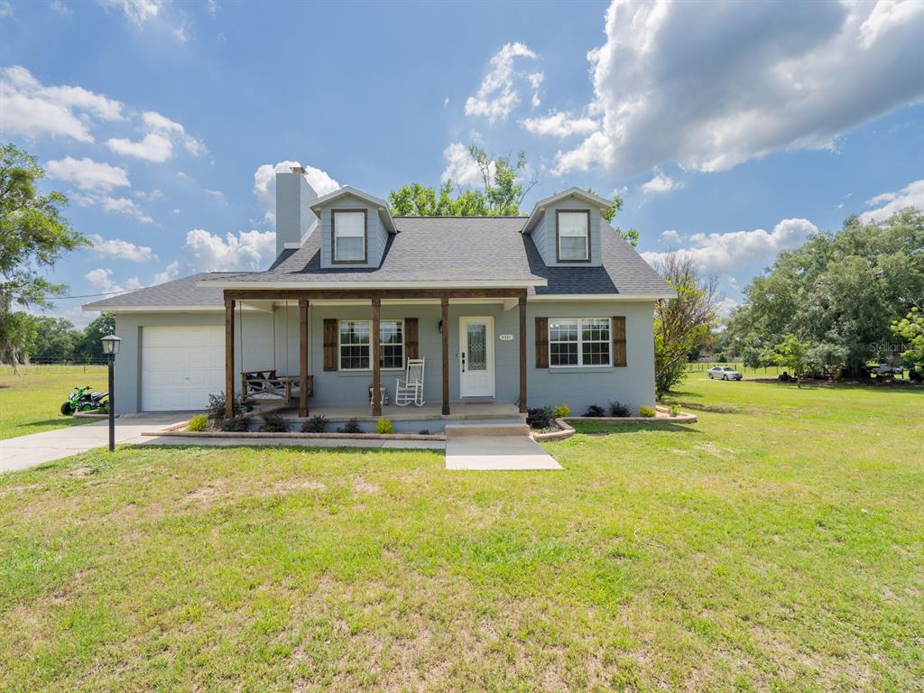 A gray, two-story house with a front porch, dormer windows, and an attached garage — 4381 NE 105TH PLACE, ANTHONY, FL