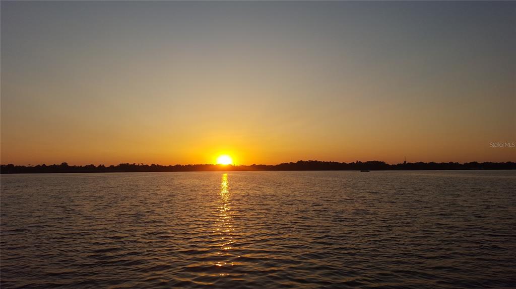 A sunset glows over a calm body of water with a distant treeline — 1670 DUCHESS DRIVE, ORLANDO, FL