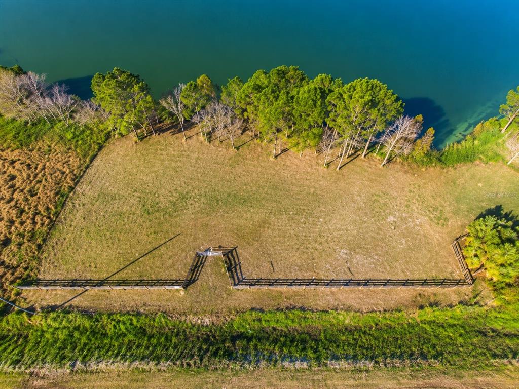 An aerial view shows a fenced, grassy lot bordering a line of trees and water — 1380 OLD BREWSTER ROAD, FORT MEADE, FL