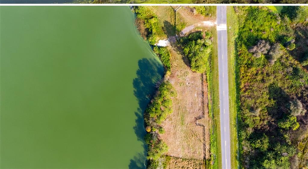 An aerial view shows a green lake next to a cleared lot and a paved road — 1380 OLD BREWSTER ROAD, FORT MEADE, FL