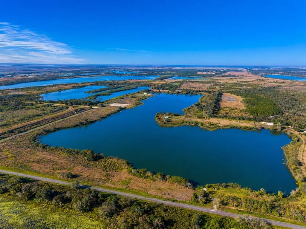An aerial view of a large lake surrounded by grassy fields and a paved road — 1380 OLD BREWSTER ROAD, FORT MEADE, FL