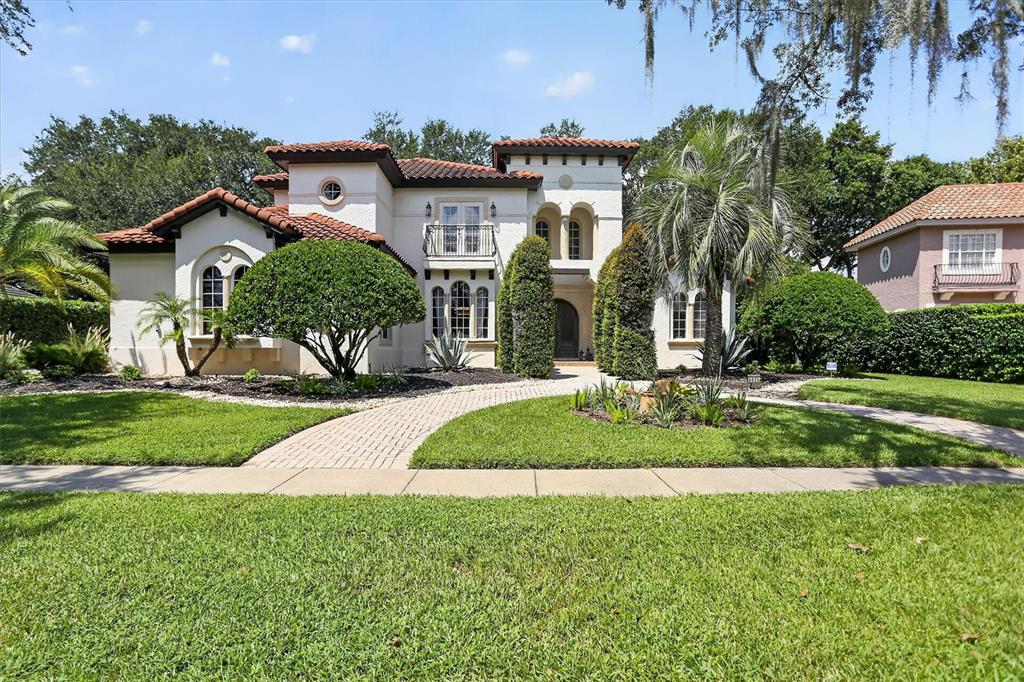 A two-story Mediterranean-style house with a tile roof, stucco exterior, and a paved walkway — 8826 SOUTHERN BREEZE DRIVE, ORLANDO, FL